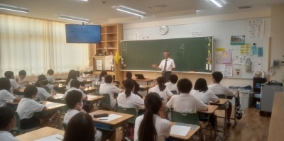 弁護士によるいじめ防止授業。教室で白いシャツを着た小学生たちが机に座り、授業を受けている様子。