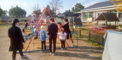 カラフルなブランコで遊んでいる幼稚園児たちと、補助する5年生たちの写真。5年生はブランコを押したり、そばで見守っている。