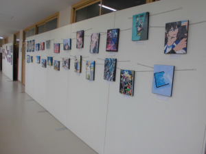 壁に多くの絵画やイラスト作品が掲示されている写真