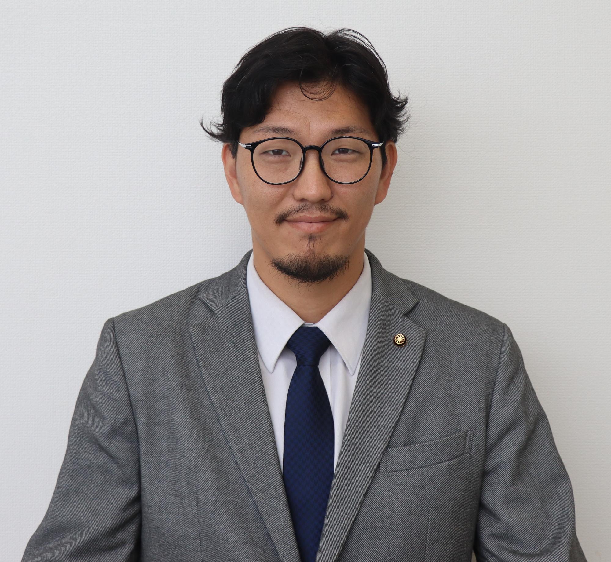 グレーのスーツ姿の男性、田中 陽介（たなか ようすけ）の写真