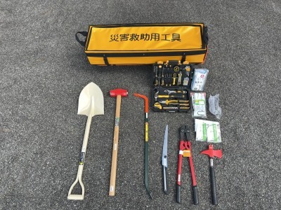 災害救助用工具と書かれた袋のようなものの手前にスコップやバールなどの工具が並んでいる写真