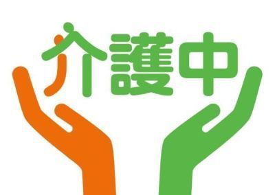 介護中の文字を両腕で支えているオレンジと緑のイラスト