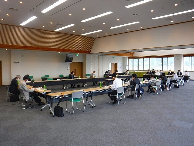 研修室内で椅子に座っている参加者の方々が書類を閲覧している様子の写真