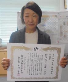 学校賞を受賞し、賞状を見せながら微笑む篠原小学校長の様子
