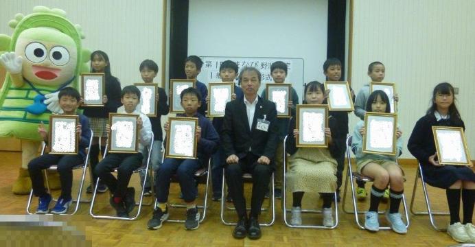 1級合格者13名と教育長ドウタクくんが記念撮影をしている様子