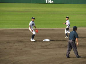 グラウンドでユニフォームを着た生徒が、野球グローブをはめて守備のようなことをしている写真