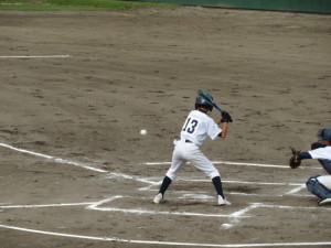 野球のユニフォームを着た生徒がバッターボックスに立ち、投げられた球を打とうとしている写真